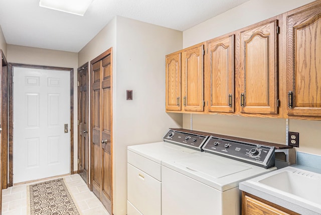 laundry room with cabinet space, washer and clothes dryer, a sink, and light tile patterned flooring