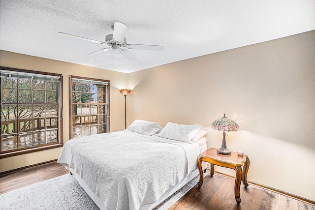 bedroom featuring baseboards, a textured ceiling, a ceiling fan, and wood finished floors