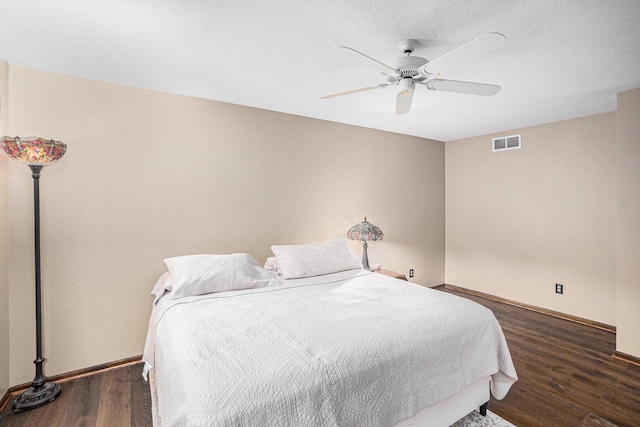 bedroom featuring visible vents, a ceiling fan, a textured ceiling, wood finished floors, and baseboards