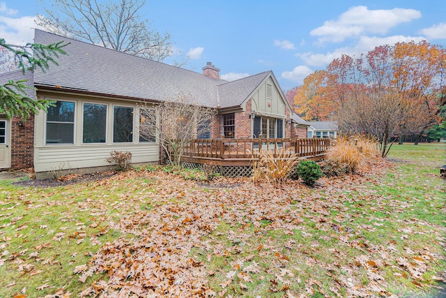 back of property with a deck, brick siding, a shingled roof, and a chimney