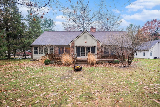 view of front of house with brick siding, roof with shingles, a wooden deck, a chimney, and a front yard