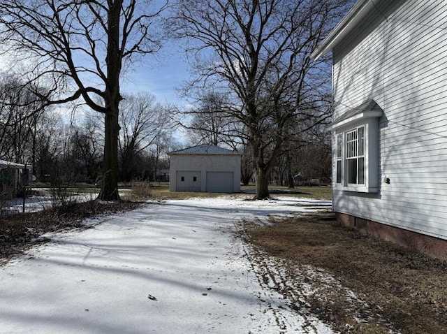 yard layered in snow featuring a garage and an outdoor structure