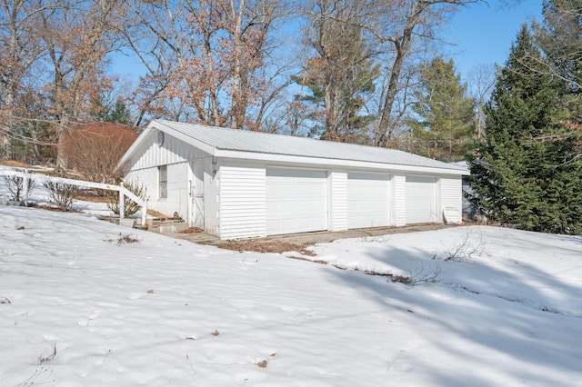 snow covered garage featuring a detached garage