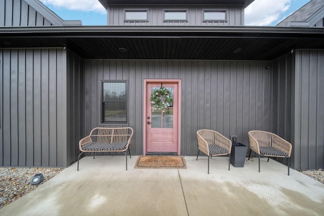 doorway to property with board and batten siding and a patio area