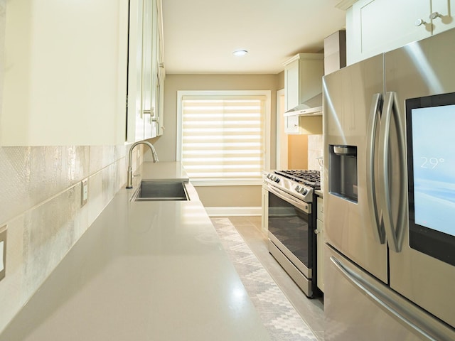 kitchen featuring tasteful backsplash, white cabinets, appliances with stainless steel finishes, light countertops, and a sink