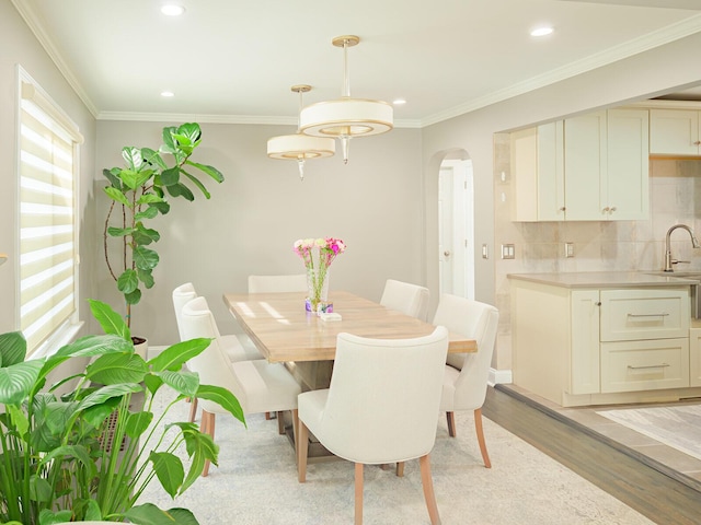 dining area featuring arched walkways, ornamental molding, recessed lighting, and light wood-style floors