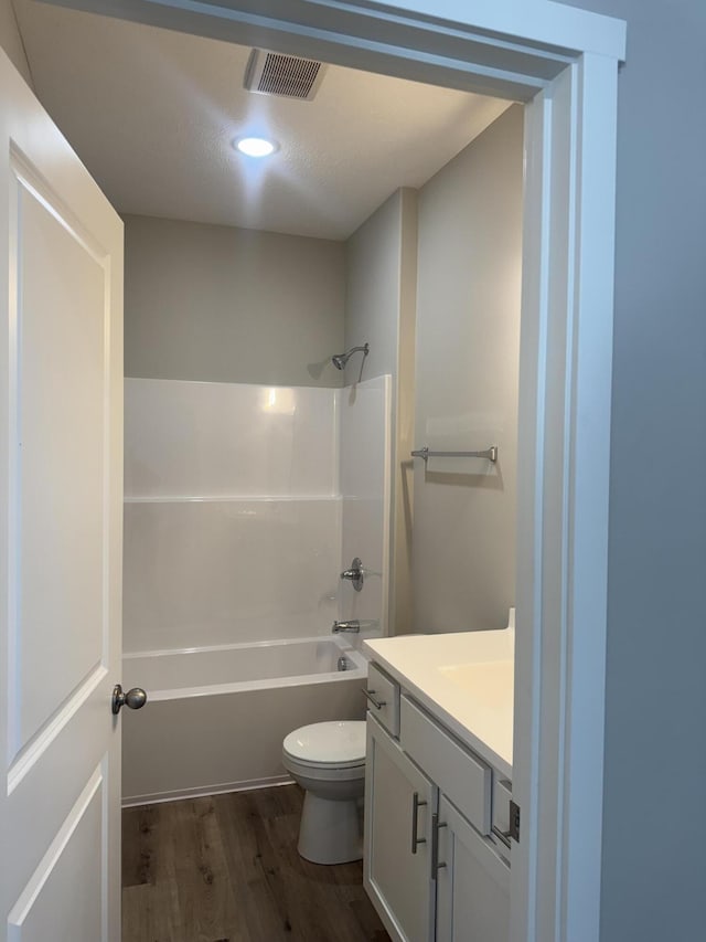 bathroom featuring visible vents, toilet, vanity, wood finished floors, and  shower combination