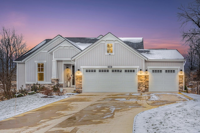 view of front of house featuring an attached garage, stone siding, board and batten siding, and concrete driveway