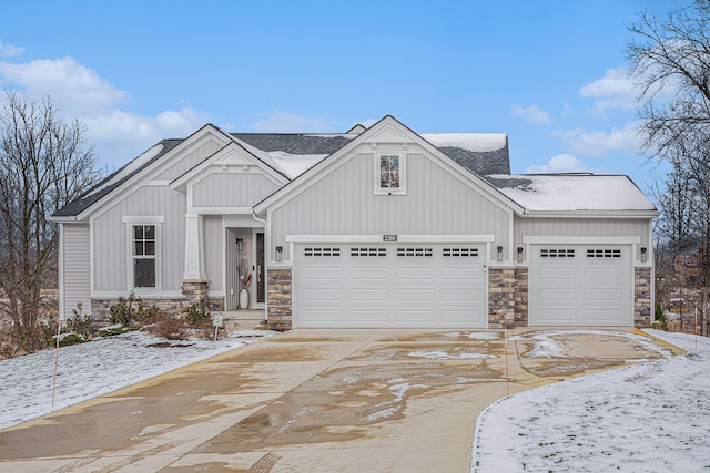 view of front of home featuring driveway, stone siding, board and batten siding, and an attached garage