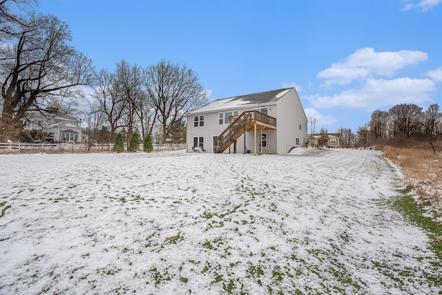 snow covered house featuring fence, stairway, and a deck