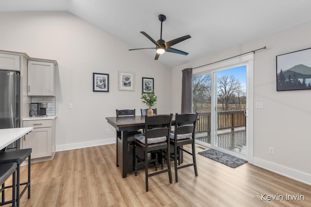 dining area featuring light wood-style floors, vaulted ceiling, and baseboards