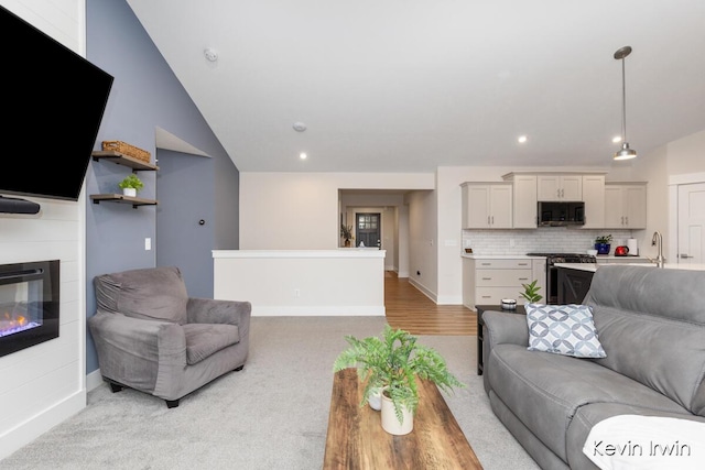 living room featuring light carpet, baseboards, a glass covered fireplace, vaulted ceiling, and recessed lighting