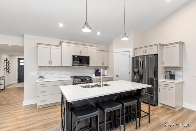 kitchen with a breakfast bar, stainless steel appliances, lofted ceiling, light countertops, and a sink