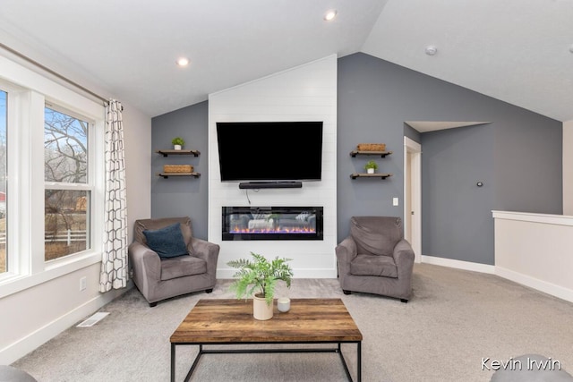 living area featuring lofted ceiling, visible vents, a large fireplace, carpet flooring, and baseboards