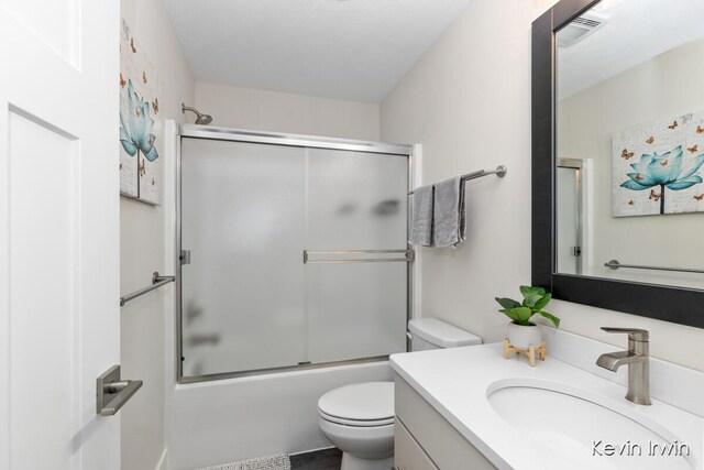 bathroom featuring toilet, enclosed tub / shower combo, visible vents, and vanity