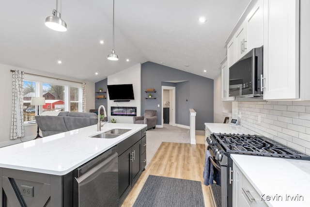 kitchen with white cabinetry, appliances with stainless steel finishes, open floor plan, and a sink