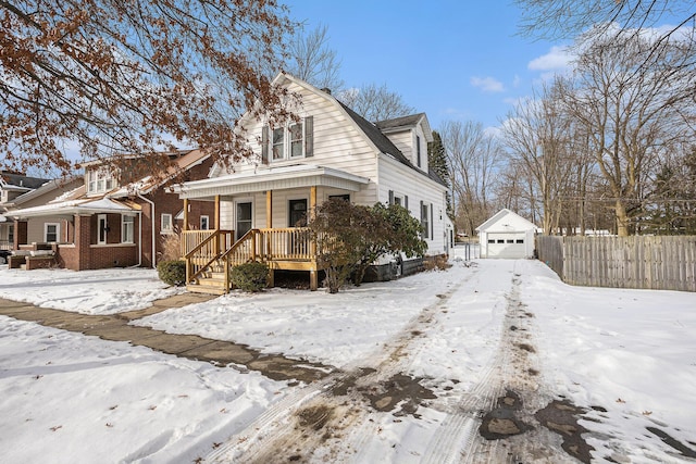 view of front of house featuring a detached garage, a porch, a gambrel roof, fence, and an outdoor structure