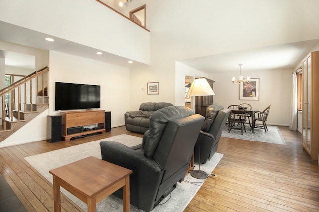 living room with stairs, light wood finished floors, baseboards, and an inviting chandelier