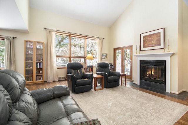 living room with a fireplace with flush hearth, a wealth of natural light, visible vents, and wood finished floors