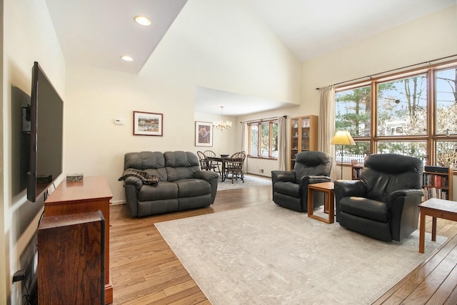 living area with baseboards, light wood-style floors, high vaulted ceiling, a notable chandelier, and recessed lighting