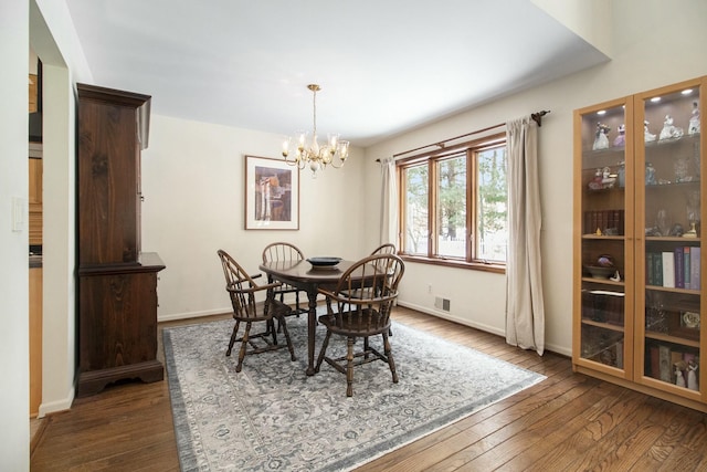 dining area with dark wood-style flooring, visible vents, a notable chandelier, and baseboards