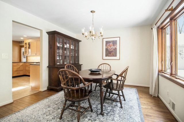 dining room featuring dark wood-style flooring, visible vents, baseboards, and an inviting chandelier