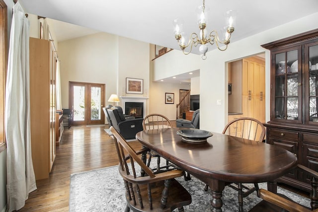 dining space with french doors, a notable chandelier, stairway, light wood-style floors, and a glass covered fireplace