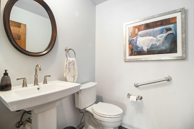 half bath featuring baseboards and toilet