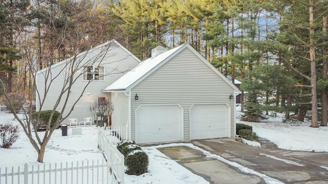 snow covered garage with fence