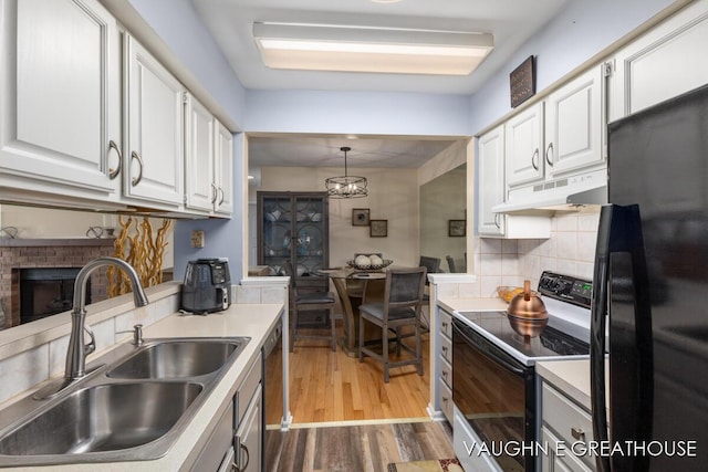 kitchen with black appliances, a sink, white cabinets, and under cabinet range hood