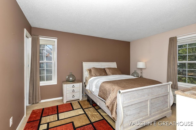 bedroom featuring baseboards, a textured ceiling, and light colored carpet