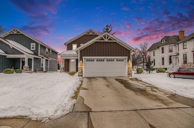 view of front of house with an attached garage, driveway, stone siding, a residential view, and board and batten siding