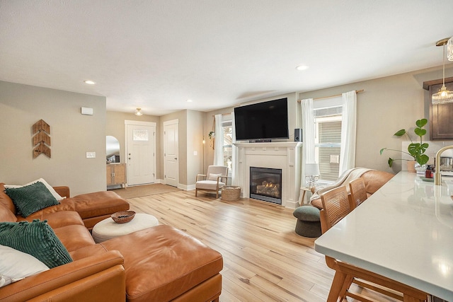 living area with light wood-style floors, recessed lighting, baseboards, and a glass covered fireplace