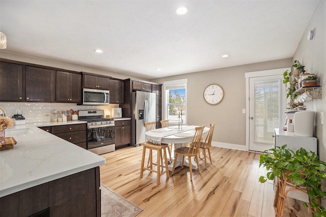 kitchen featuring light wood-type flooring, dark brown cabinetry, baseboards, and appliances with stainless steel finishes