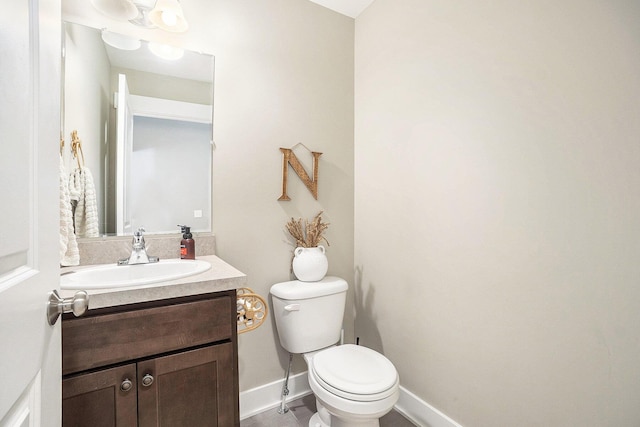 half bathroom featuring toilet, vanity, and baseboards