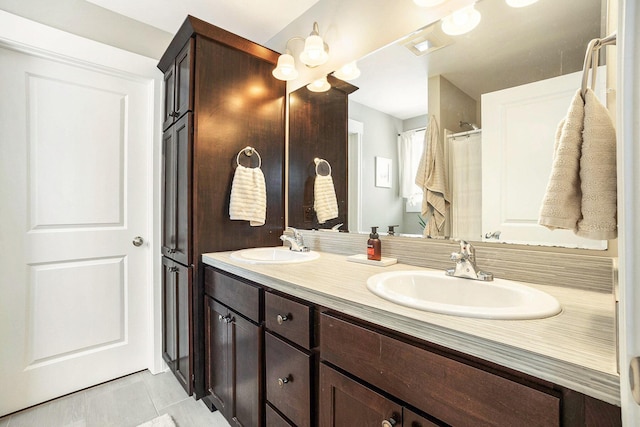 full bath featuring double vanity, a sink, and tile patterned floors