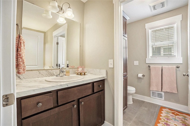 bathroom with baseboards, visible vents, vanity, and toilet