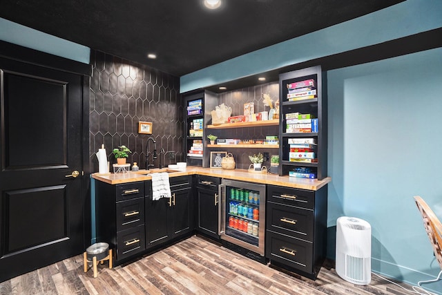 bar with wine cooler, recessed lighting, light wood-style flooring, and wet bar