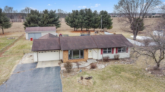 view of front of house with aphalt driveway, brick siding, fence, a garage, and a front lawn