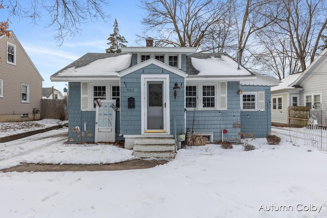 bungalow-style home with a chimney and fence