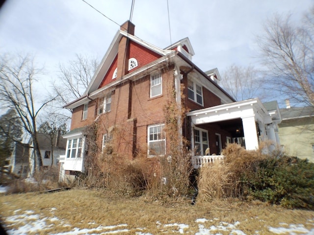 view of snow covered exterior with brick siding and a chimney