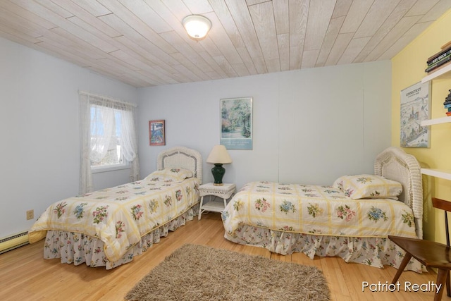 bedroom with wood ceiling, a baseboard heating unit, and wood finished floors