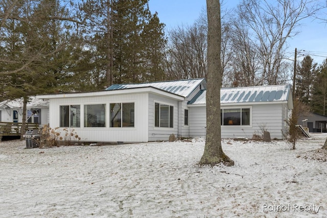 snow covered rear of property with metal roof