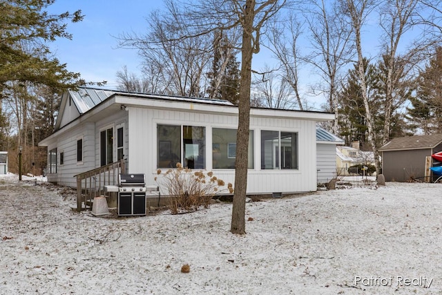 rear view of property featuring entry steps and metal roof