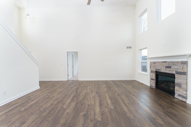 unfurnished living room featuring visible vents, dark wood-style flooring, a fireplace, and a wealth of natural light