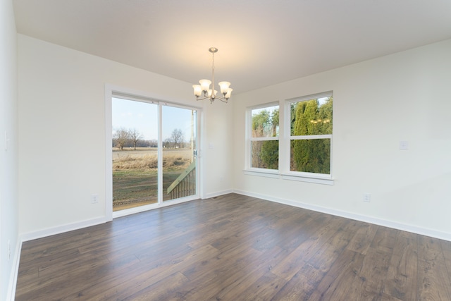 empty room with baseboards, dark wood-type flooring, and a notable chandelier