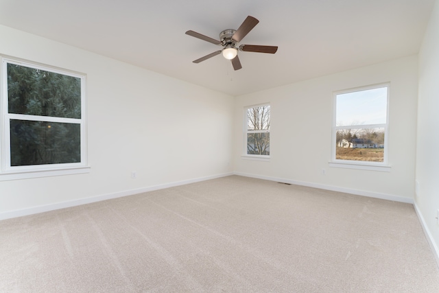 unfurnished room featuring a ceiling fan, light colored carpet, visible vents, and baseboards