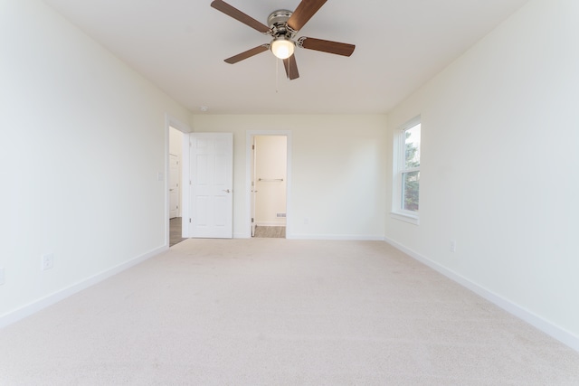 spare room featuring a ceiling fan, light colored carpet, and baseboards