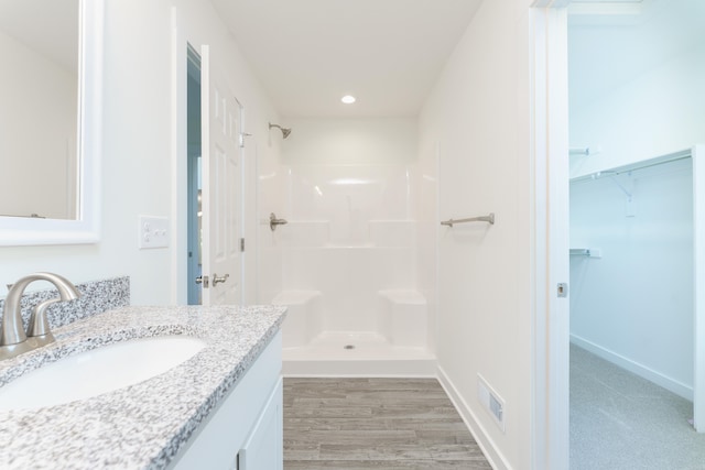 full bath featuring baseboards, visible vents, wood finished floors, vanity, and a shower stall