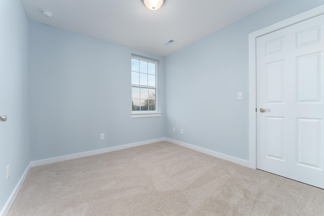 empty room with light carpet, visible vents, and baseboards